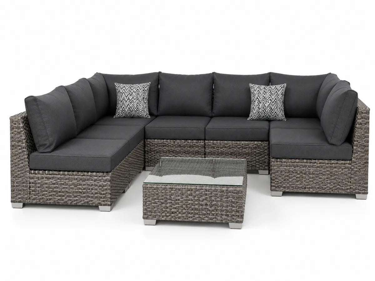 Narożna sofa ogrodowa z technorattanu z szklanym stolikiem i szarymi poduszkami