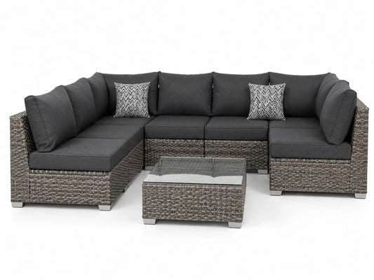 Narożna sofa ogrodowa z technorattanu z szklanym stolikiem i szarymi poduszkami